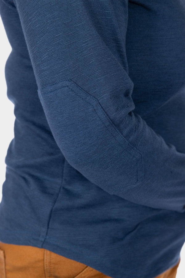 Detail view of the Dovetail Workwear Honed Long Sleeve Thermal Henley in Atlantic Blue, highlighting the reinforced elbow and waffle knit thermal fabric on a woman