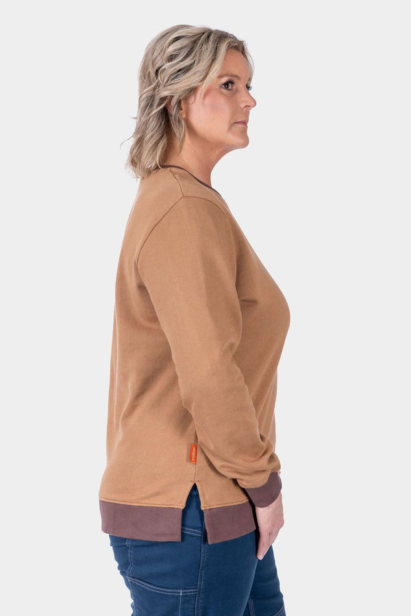 Side view of a woman wearing the Dovetail Workwear GO TO™ Crew Sweatshirt in Saddle Brown/Kodiak Brown with ribbed trim and cuffs, paired with dark jeans