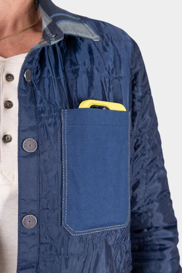Detail shot of the Durham Reversible Quilted Shirt Jac by Dovetail Workwear in Loden Green Plaid or Barn Red Plaid, highlighting the canvas pocket with item inside
