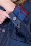 Close-up detail of the Durham Reversible Quilted Shirt Jac by Dovetail Workwear showing the loden green plaid quilted side with secured pocket and metal button fastening