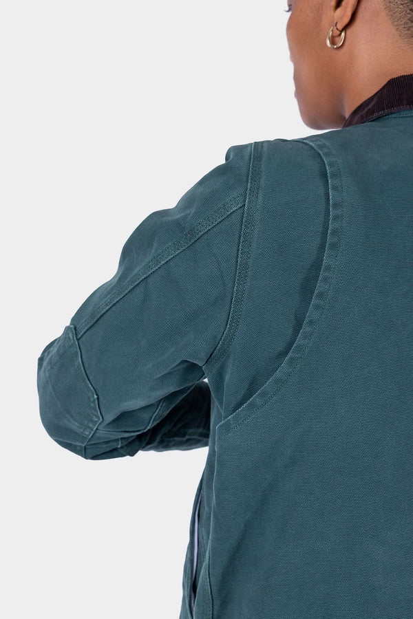 Back view of a woman wearing the Dovetail Workwear Old School Trucker Canvas Work Jacket in Lodge Green, highlighting the bi-swing back pleats and heavy-duty duck canvas construction