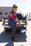 Woman wearing the Barn Red Plaid Durham Reversible Quilted Shirt Jac from Dovetail Workwear while organizing tools in a truck bed