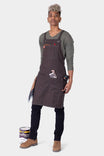 Dovetail Workwear Obana Work Apron in Kodiak Brown worn by a woman with cross-back straps, 8 pockets, and tool storage displayed against a white background