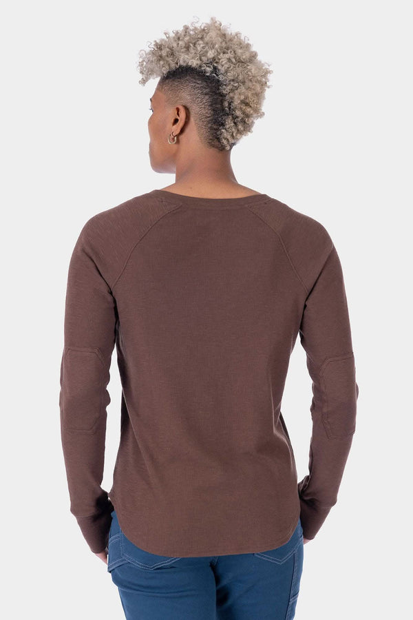 Back view of a woman wearing the Dovetail Workwear Honed Long Sleeve Thermal Henley in Kodiak Brown with blue jeans, showcasing the waffle knit fabric and reinforced elbows