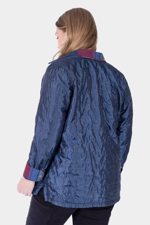 Back view of a woman wearing the Dovetail Workwear Durham Reversible Quilted Shirt Jac in Loden Green Plaid