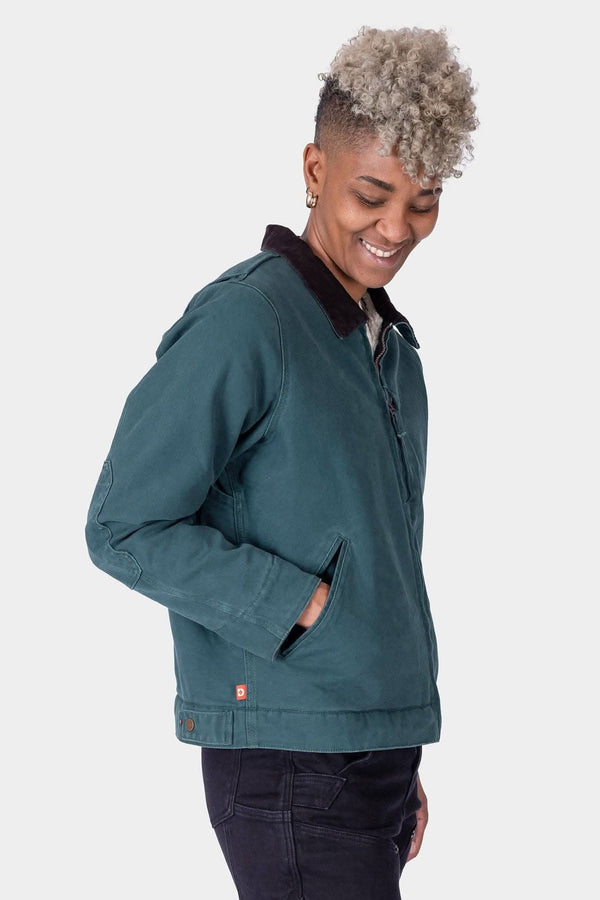Side view of a woman wearing the Dovetail Workwear Old School Trucker Canvas Work Jacket in Lodge Green, featuring faux shearling lining and corduroy collar