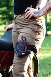 Black Rae Ripple x Dovetail Workwear Brave Wings Bandana tied around a woman's leg while she sits outdoors, showcasing the hand-drawn wing and flower artwork design