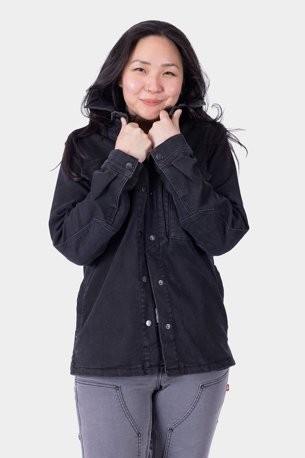 Black Oahe HOTSWAP™ Thermal Denim Work Jacket by Dovetail Workwear shown on a woman, featuring wind-resistant HotSwap™ stretch denim with reinforced elbows and multiple pockets
