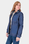 Side view of a woman wearing the Dovetail Workwear Durham Reversible Quilted Shirt Jac in Loden Green Plaid with quilted and solid paneling, paired with matching denim pants