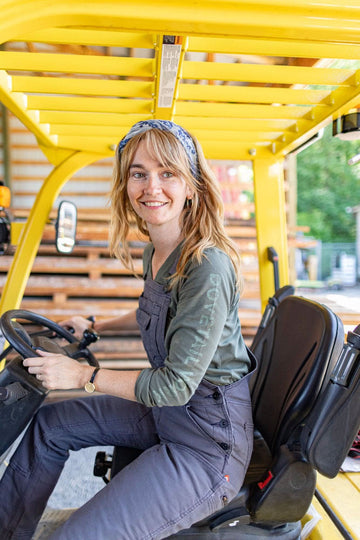 Woman seated in a yellow vehicle wearing the Carver Wool Wild Rag Bandana in Navy, tied around her neck