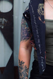 Rae Ripple x Dovetail Workwear Brave Wings Bandana in black styled as a wild rag around a woman's arm, displaying hand-drawn wing and flower artwork and inspirational text
