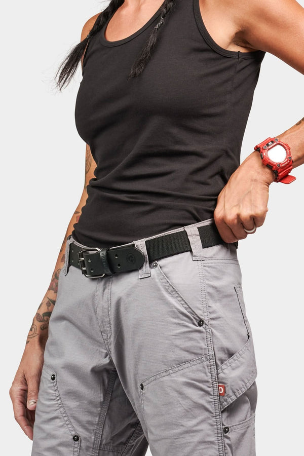 Woman wearing Dovetail Workwear's Flex Work Belt in black, featuring a double-pronged buckle and elastic back panel, paired with gray cargo pants