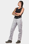 Woman wearing Dovetail Workwear Anna Ultralight Trail Pant in Dove Grey Ripstop, standing in side profile with arms crossed, showcasing the relaxed leg fit and reinforced knee design