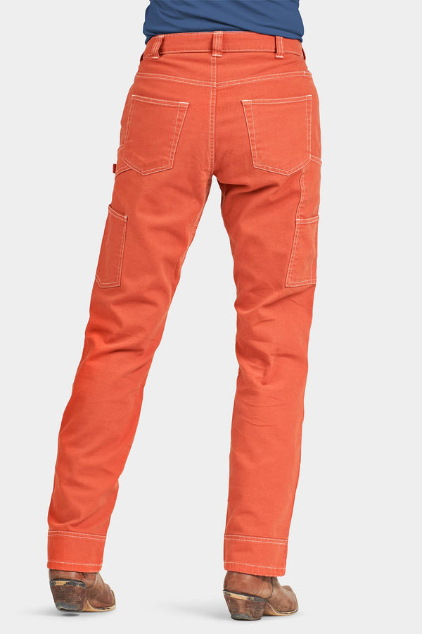 Back view of a woman wearing Dovetail Workwear's Anna Taskpant in Paprika Canvas, featuring nested pockets, reinforced knees, and contrast stitching
