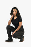 Woman crouching in Dovetail Workwear GO TO™ Stretch Canvas Pant in Carbon Black, showcasing the straight leg fit, tool loop, and nested pockets