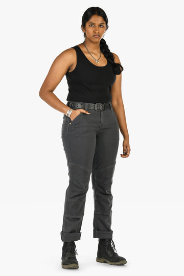 Woman wearing Dovetail Workwear GO TO™ Stretch Canvas Pant in Cement Grey with straight leg, tool loop, and reinforced knee, styled with black tank top and boots