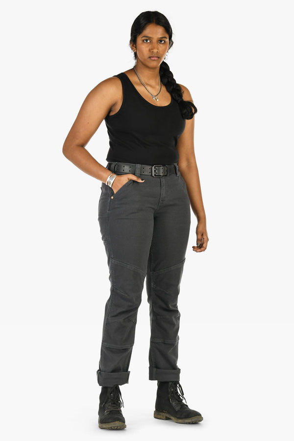 Woman wearing Dovetail Workwear GO TO™ Stretch Canvas Pant in Cement Grey with straight leg, tool loop, and reinforced knee, styled with black tank top and boots