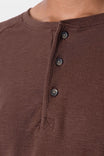 Detail shot of the Dovetail Workwear Honed Long Sleeve Thermal Henley in Kodiak Brown, showing the button front placket and waffle knit thermal fabric worn by a woman