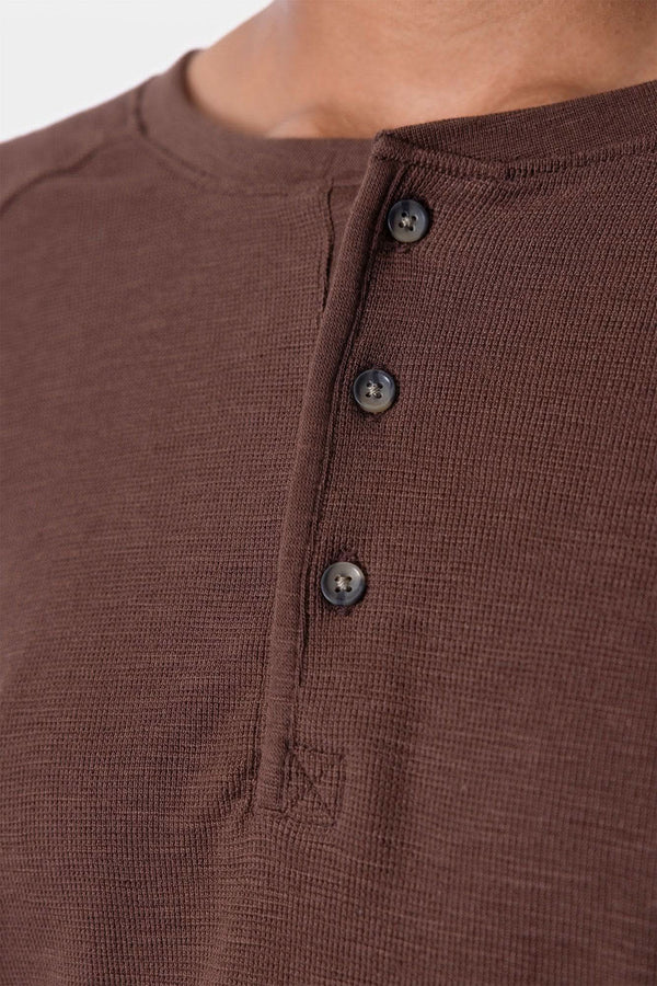 Detail shot of the Dovetail Workwear Honed Long Sleeve Thermal Henley in Kodiak Brown, showing the button front placket and waffle knit thermal fabric worn by a woman