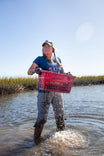 Woman wading in water wearing Dovetail Workwear Anna Ultralight Trail Pant in Dove Grey Ripstop, demonstrating water-resistant and quick-dry features in outdoor conditions