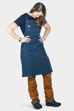 Back view of a woman wearing the Dovetail Workwear Obana Work Apron in Dark Blue Wabash Stripe, displaying dual slash pockets and cross-back straps