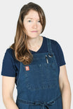 Woman wearing the Dovetail Workwear Obana Work Apron in Dark Blue Wabash Stripe, displaying front pockets and cross-back straps designed for tool organization