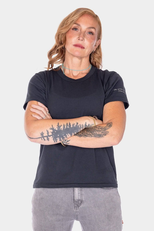 Woman wearing the black Rae Ripple x Dovetail Workwear Brave Wings T-Shirt, displaying the design on the back with arms crossed