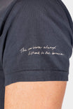 Close-up detail of the Rae Ripple x Dovetail Workwear Brave Wings T-Shirt in black, showing the handwritten mantra "The universe always listens to the brave" printed on the left sleeve