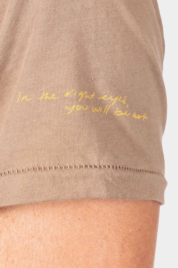 Detail view of the Rae Ripple x Dovetail Workwear You Will Be Art T-Shirt in Alloy Brown, showing handwritten text on the left sleeve