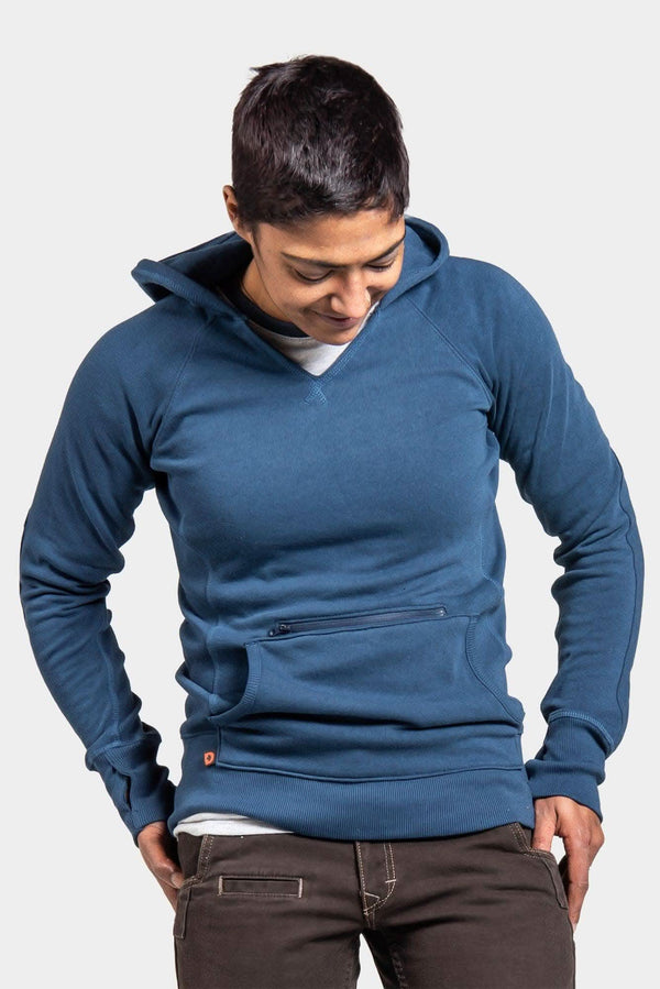 Woman wearing the Anna Pullover Hoodie in Dovetail Blue by Dovetail Workwear, looking down at the zip pocket and handwarmer front pocket details