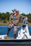 Woman standing on a boat wearing Dovetail Workwear's Anna Ultralight Trail Pant in Dove Grey Ripstop, demonstrating the durable work pants' relaxed fit and reinforced knees for outdoor activities