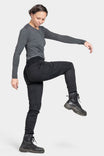 Woman wearing Dovetail Workwear Christa DIY Pant in Black Performance Modal, demonstrating the reinforced knees and slim leg fit while performing a high kick motion