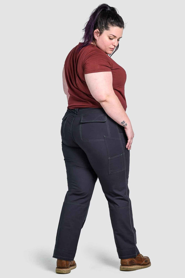 Back view of a woman wearing Dovetail Workwear's Day Construct Pant in Lightweight Dark Navy Ripstop, showing relaxed leg, reinforced knees, and functional pockets