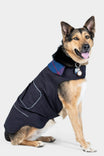 German Shepherd dog wearing the black Shop Dog Jacket with flannel collar and visible pockets, sitting against a white background