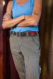Dovetail Workwear Flex Work Belt in Black with double-pronged buckle worn by a woman in blue tank top and grey work pants, shown from waist down