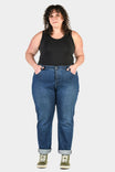 Pride Shop Pant in Indigo Denim Blue by Dovetail Workwear, shown on a woman wearing a black tank top and olive green high-top sneakers with cuffed inseams