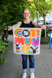 Woman holding Lisa Congdon's Pocket Pride Bandana by DoveLab™, displaying its vibrant rainbow colors and geometric designs inspired by the Progress Pride flag
