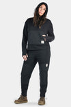 Woman modeling the Dovetail Workwear Flagger Fleece Jogger Work Pant in Black, featuring reinforced knees, tapered legs, and elastic cuffs
