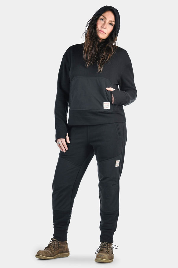 Woman modeling the Dovetail Workwear Flagger Fleece Jogger Work Pant in Black, featuring reinforced knees, tapered legs, and elastic cuffs