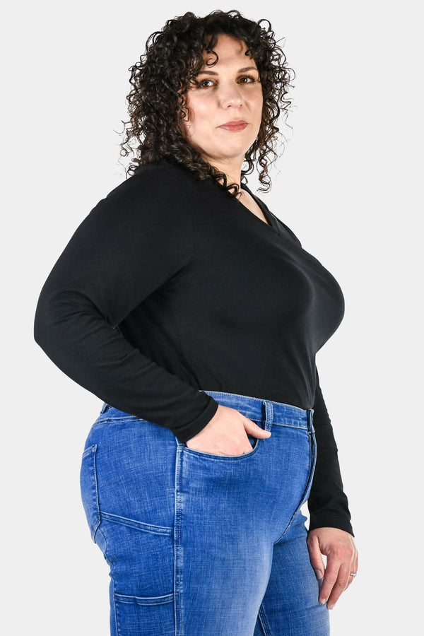 Side view of a woman wearing the Dovetail Workwear Long Sleeve V-Neck Tee in black with blue jeans, showcasing the relaxed fit and extra coverage