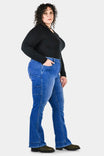 Side view of a woman wearing Dovetail Workwear DX Bootcut Pant in Blue Sky Denim, showcasing the bootcut silhouette, nested pockets, and tool loop detail