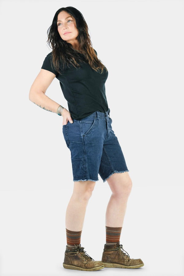 Wabash Work Short in Wabash Stripe by Dovetail Workwear, shown on a woman from the side with an 8-inch inseam, frayed cuff, and tool loop detail