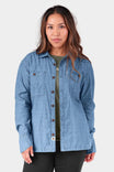 Woman wearing the John Deere X Dovetail Cultivator Work Shirt in Indigo Blue Dobby with long sleeves and reinforced elbows over a layered outfit