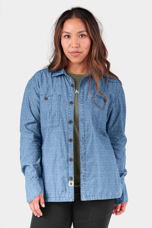 Woman wearing the John Deere X Dovetail Cultivator Work Shirt in Indigo Blue Dobby with long sleeves and reinforced elbows over a layered outfit