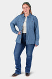 Woman wearing John Deere X Dovetail Workwear Cultivator Work Shirt in indigo blue dobby with long sleeves, paired with dark jeans and a green cap