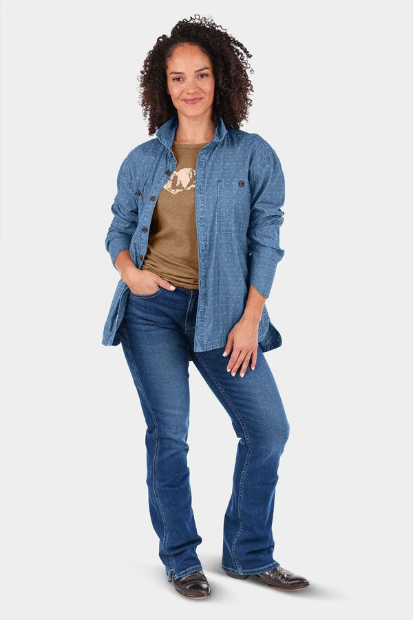 Woman wearing the John Deere X Dovetail Cultivator Work Shirt in Indigo Blue Dobby over a tan graphic tee, paired with dark blue jeans