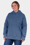 Woman wearing the John Deere X Dovetail Workwear Early Bird Hoodie in Steel Blue, featuring a cowl neck, front pouch pocket, and thumbholes