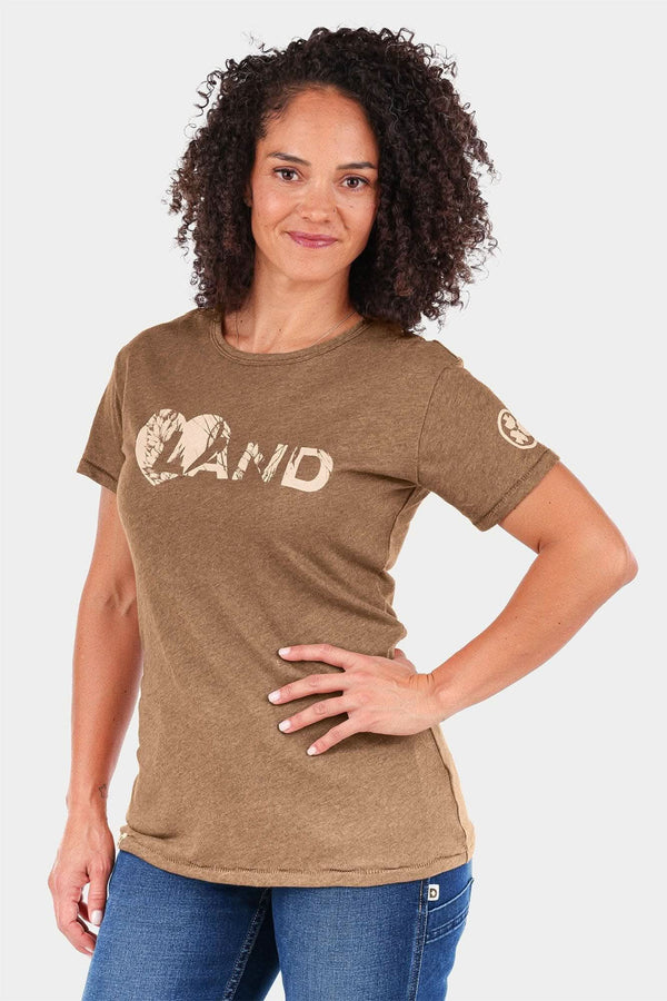 John Deere X Dovetail Workwear Heartland T-Shirt in Sawdust Brown worn by a woman, featuring a graphic logo and short sleeves