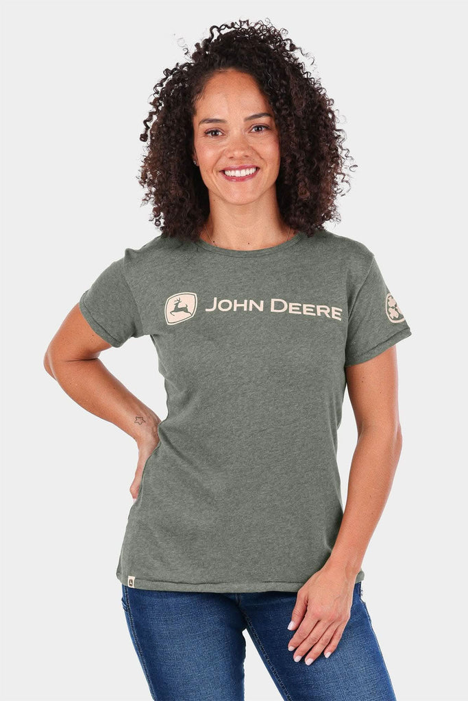 John Deere X Dovetail Workwear T-Shirt for Women in Heathered Green, worn by a smiling woman with curly dark hair, featuring the iconic deer logo and brand text on the chest
