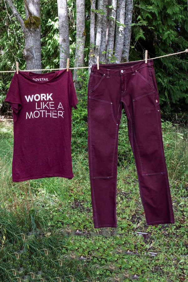 Elderberry Dovetail Workwear Anna Taskpant canvas work pants hung on a clothesline, displayed alongside a matching maroon graphic tee